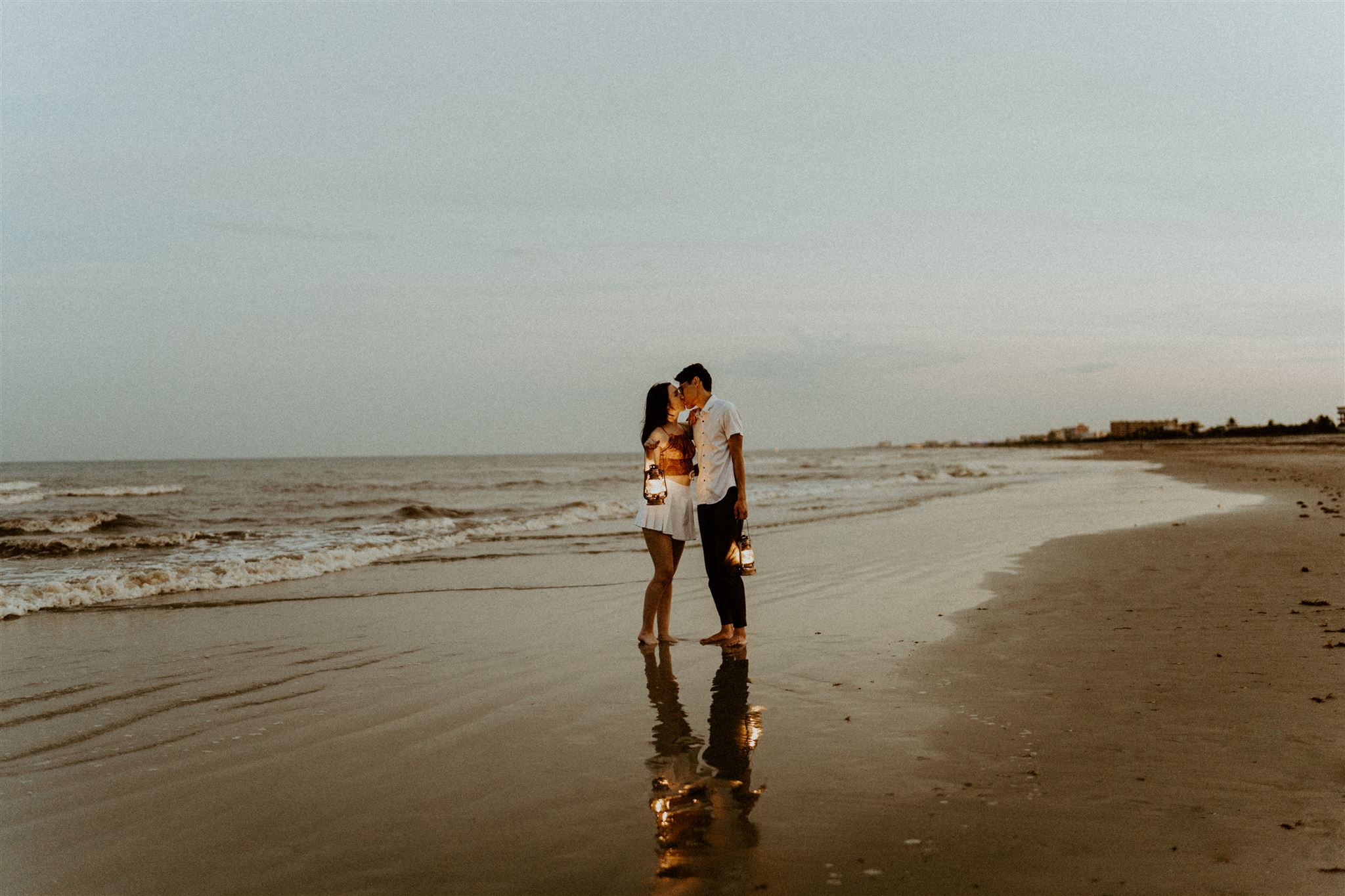 Surprise beach proposal during twilight hour with lanterns