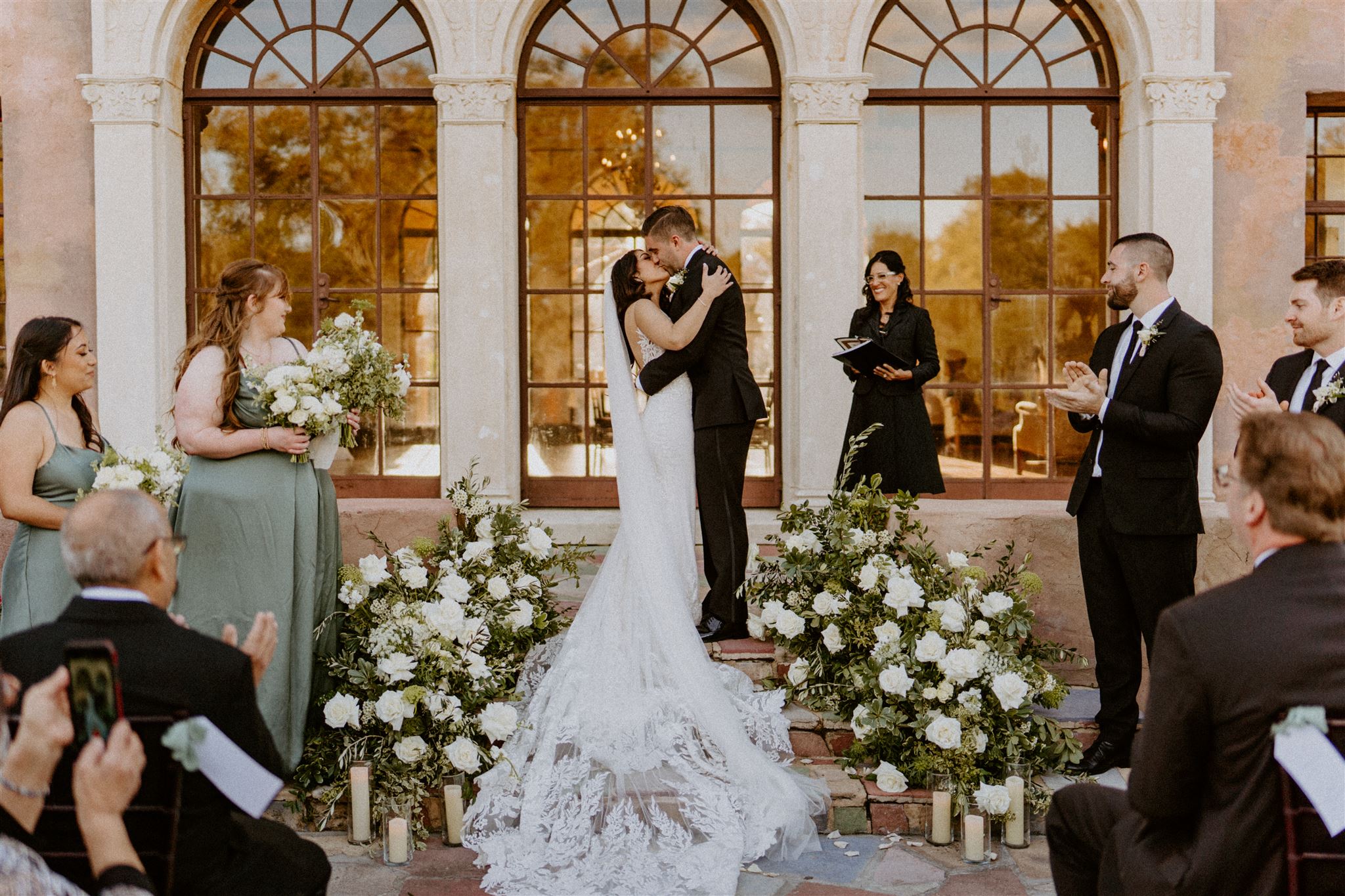 Bride and groom's first kiss in front of the Howey Mansion's rustic stone steps by the arch windows as the wind flows through the bride's veil