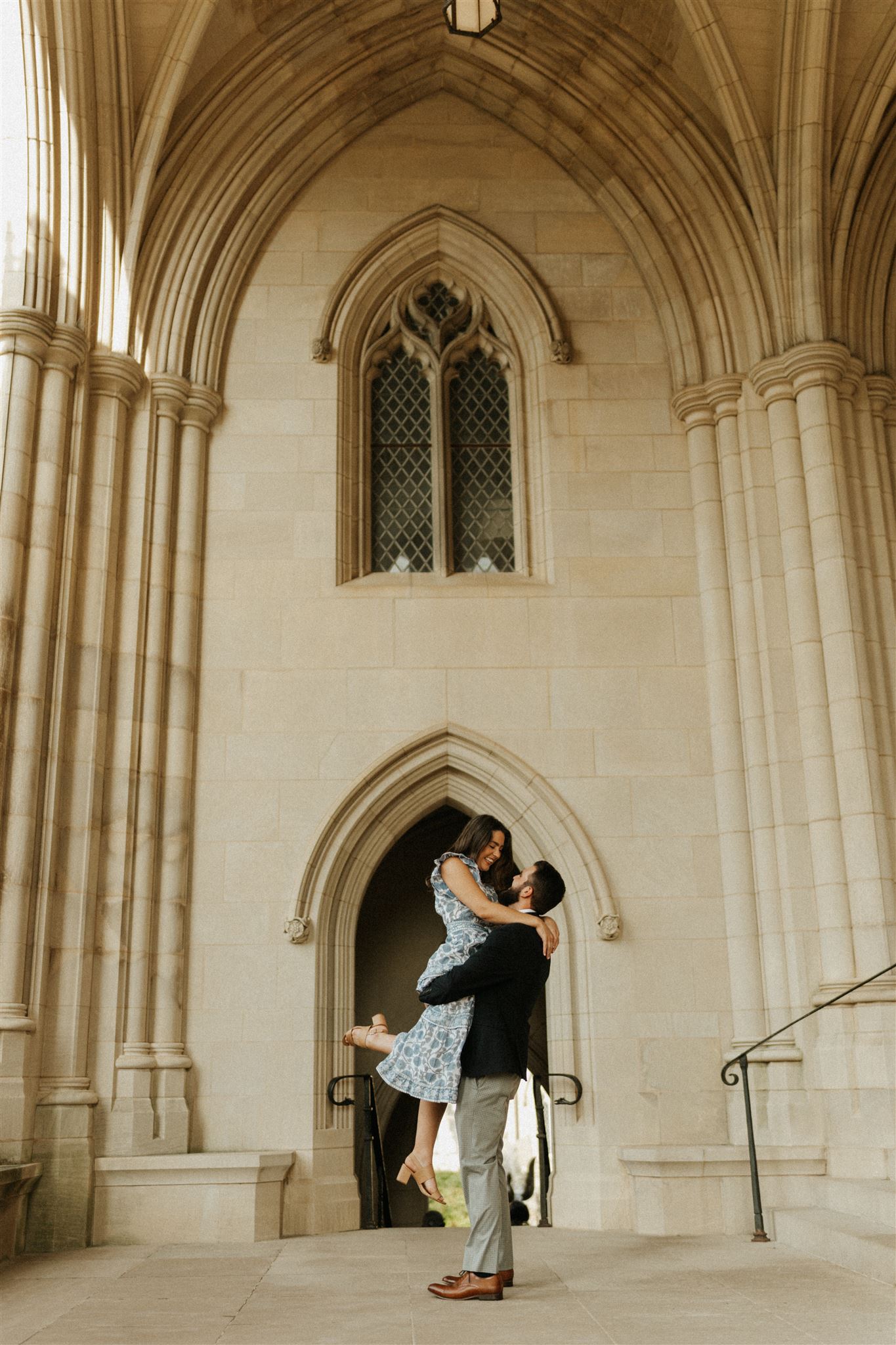 engaged couple picking each other up and swinging each other around at the National Cathedral in Washington DC